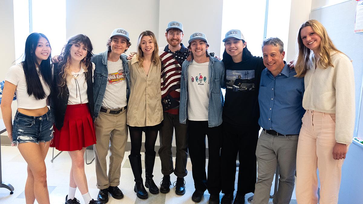 Group photo in a classroom of associate professor Marc Cohen and six students from his English 105 class with the two band members of Hotel Fiction, Jess Thompson and Jade Long.